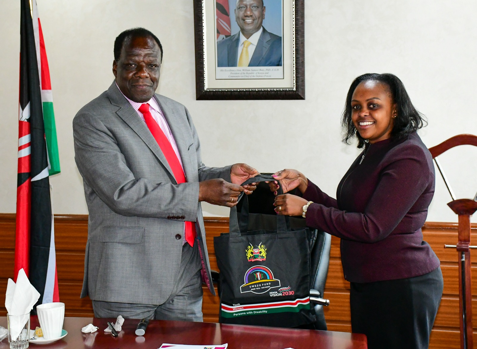 CS. Cooperatives and MSME Hon. Oparanya receives a gift basket from Uwezo Fund board chairperson
